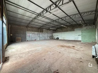 Imagem de um espaço industrial com teto de metal e piso de concreto.
