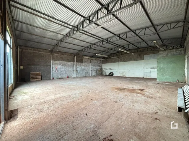 Imagem de um espaço industrial com teto de metal e piso de concreto.