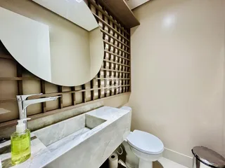 Banheiro com pia de mármore e vaso sanitário branco.