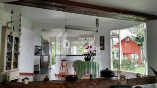 Ambiente interno com vigas de madeira e vista para o exterior.