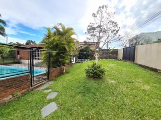Vista de um jardim gramado com cerca e água ao fundo.