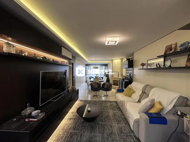 Foto da sala de estar moderna com sofá e televisão em um apartamento.