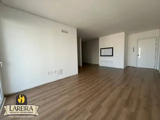 Interior de um ambiente com piso de madeira clara e paredes brancas.