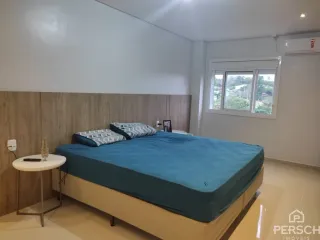 Quarto com cama de casal e cabeceira de madeira clara.