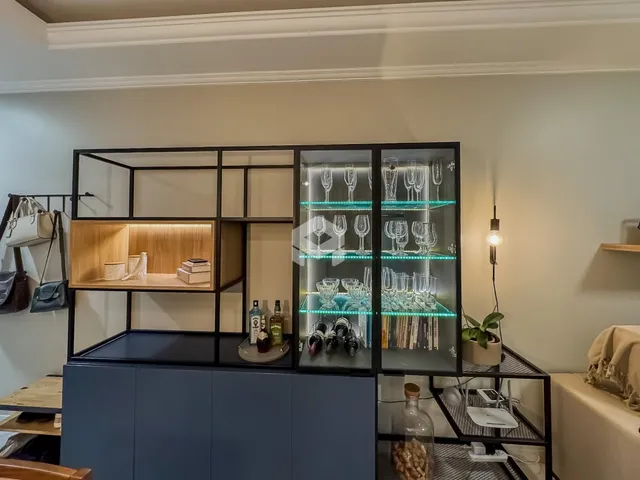 Uma sala de estar com estantes de metal exibindo garrafas de vinho.