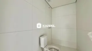 Banheiro com vaso sanitário e paredes brancas.