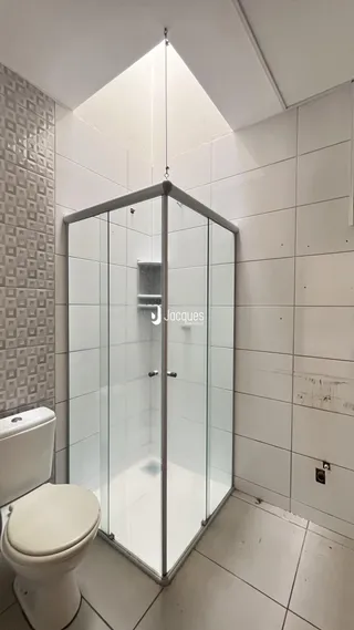 Foto de um banheiro com box de vidro e vaso sanitário.
