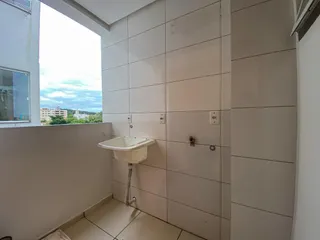 Banheiro com revestimento de azulejos brancos e pia de apoio.
