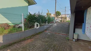Vista externa da propriedade mostrando o muro e o caminho de acesso.