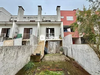 Vista externa de um prédio residencial com escadaria e muro de concreto.