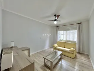 Sala de estar com sofá amarelo e piso de madeira clara.