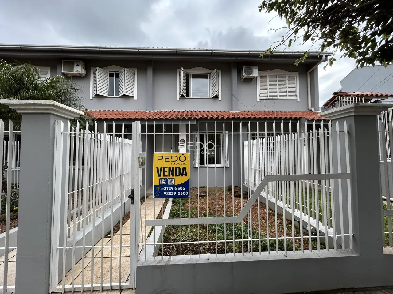 Fachada de uma casa em Lajeado, Brasil, com cerca e portão de metal branco.