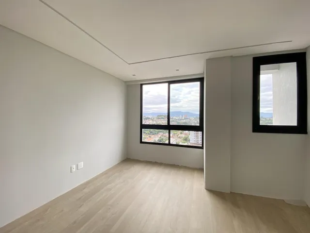 Uma sala de estar clara com piso de madeira e grande janela com vista da cidade.