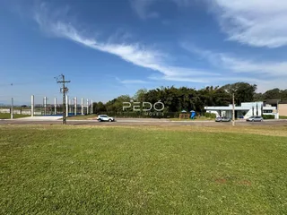 Vista externa de um terreno gramado com uma edificação ao fundo.
