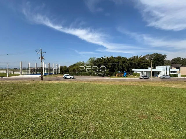 Vista externa de um terreno gramado com uma edificação ao fundo.