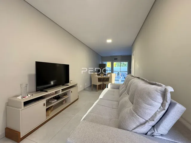 Sala de estar moderna com sofá e televisão em um ambiente claro.