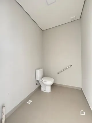 Um corredor interno com um vaso sanitário branco.