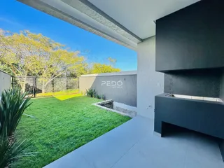 Vista de um jardim gramado e área externa de uma residência.