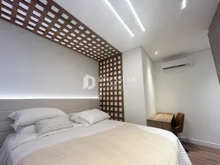 Quarto com cabeceira e teto de treliça de madeira.