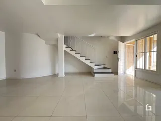 Ambiente interno amplo com piso de cerâmica e escadaria branca.
