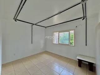 Ambiente interno de uma sala com piso de cerâmica e vigas expostas.
