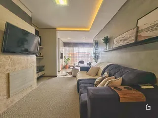 Sala de estar moderna com sofá e televisão em um apartamento no Brasil.
