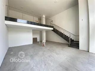 Vista interna de um espaço aberto com escadaria e mezanino em uma residência.