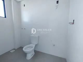 Um banheiro interno com paredes brancas e piso cinza.