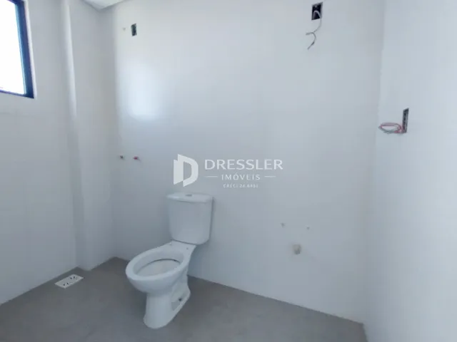 Um banheiro interno com paredes brancas e piso cinza.