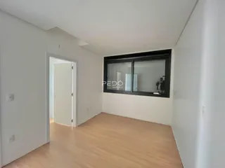 Interior de um ambiente com piso de madeira clara e paredes brancas.