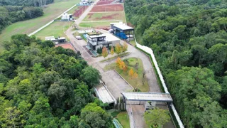 Vista aérea de um terreno com construções em área de mata densa.