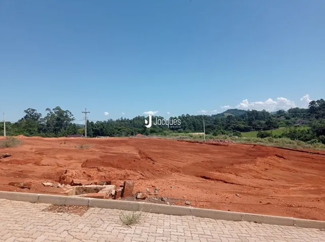 Vista do terreno com solo avermelhado sob céu azul.