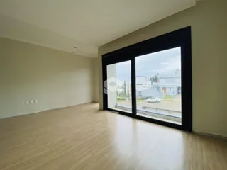 Ambiente interno de uma sala com piso de madeira clara e grande janela.