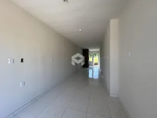 Corredor interno de uma residência com paredes brancas e piso de cerâmica clara.