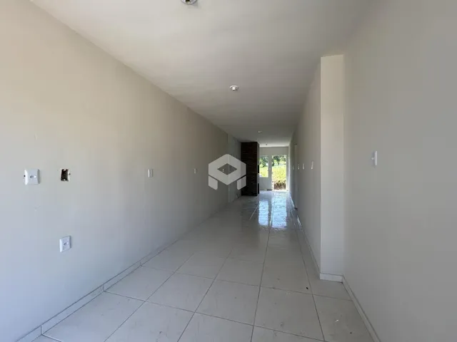 Corredor interno de uma residência com paredes brancas e piso de cerâmica clara.