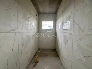 Foto de um corredor com paredes de mármore branco e piso de concreto.