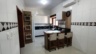 Cozinha com armários brancos e bancadas escuras em um imóvel.