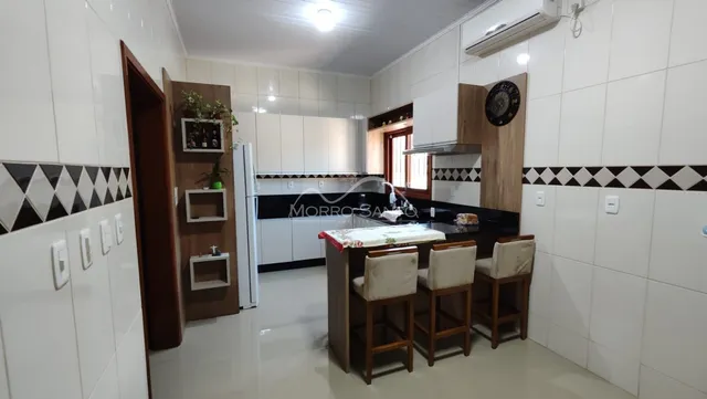Cozinha com armários brancos e bancadas escuras em um imóvel.
