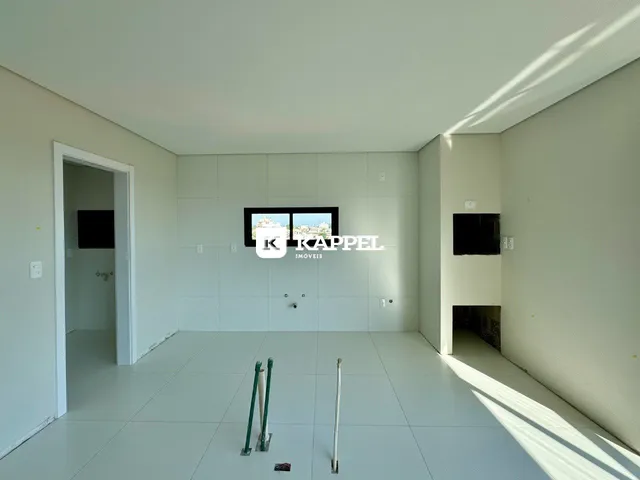 Ambiente interno de uma sala ampla com piso de cerâmica e paredes brancas.