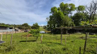 Vista de um campo gramado com árvores e um corpo d'água ao fundo.