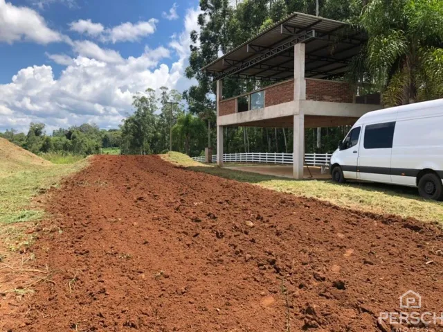 Foto de um terreno com terra vermelha solta em uma área externa.