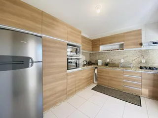 Esta é uma foto de uma cozinha moderna com armários de madeira e bancadas claras.