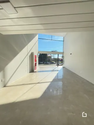 Espaço interno amplo com piso de concreto polido e vista para o exterior.