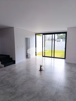 Ambiente interno amplo com piso de cerâmica claro e portas de vidro.