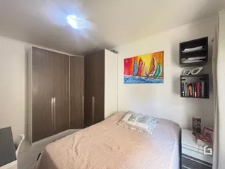 Quarto com armários em madeira e cama no interior de uma residência.