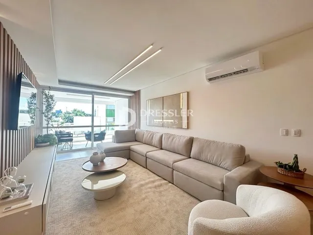 Sala de estar com sofá e grandes janelas.