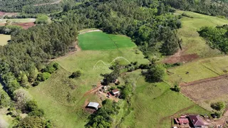 Vista aérea de uma propriedade rural com campos verdes e vegetação densa.