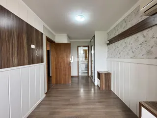 Vista do corredor interno de uma residência com piso de madeira e painéis.