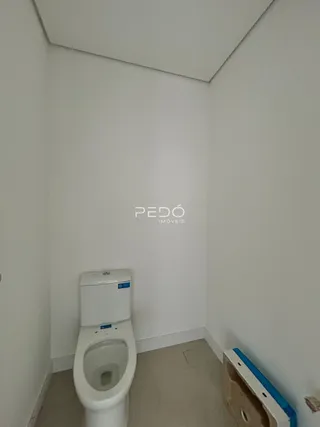 Vista de um corredor interno com um vaso sanitário branco e paredes brancas.