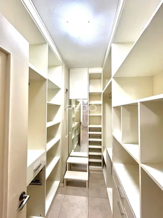 Hall de entrada com estantes brancas em um apartamento.